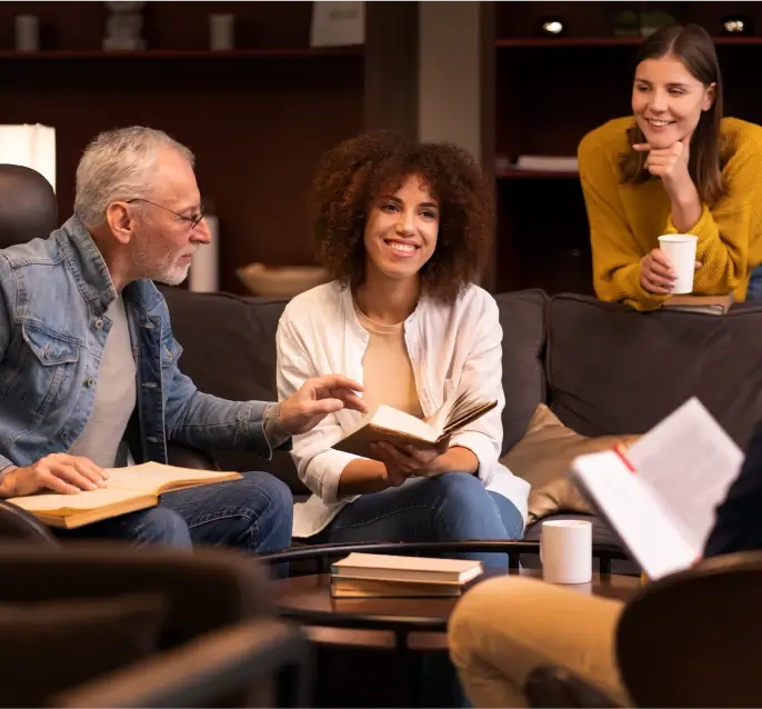 four people sitting together with book and talking with each other