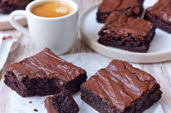 two plates with brownies next to a cup of coffee